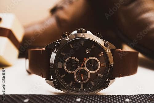 Mans brown leather watch with shoes in background