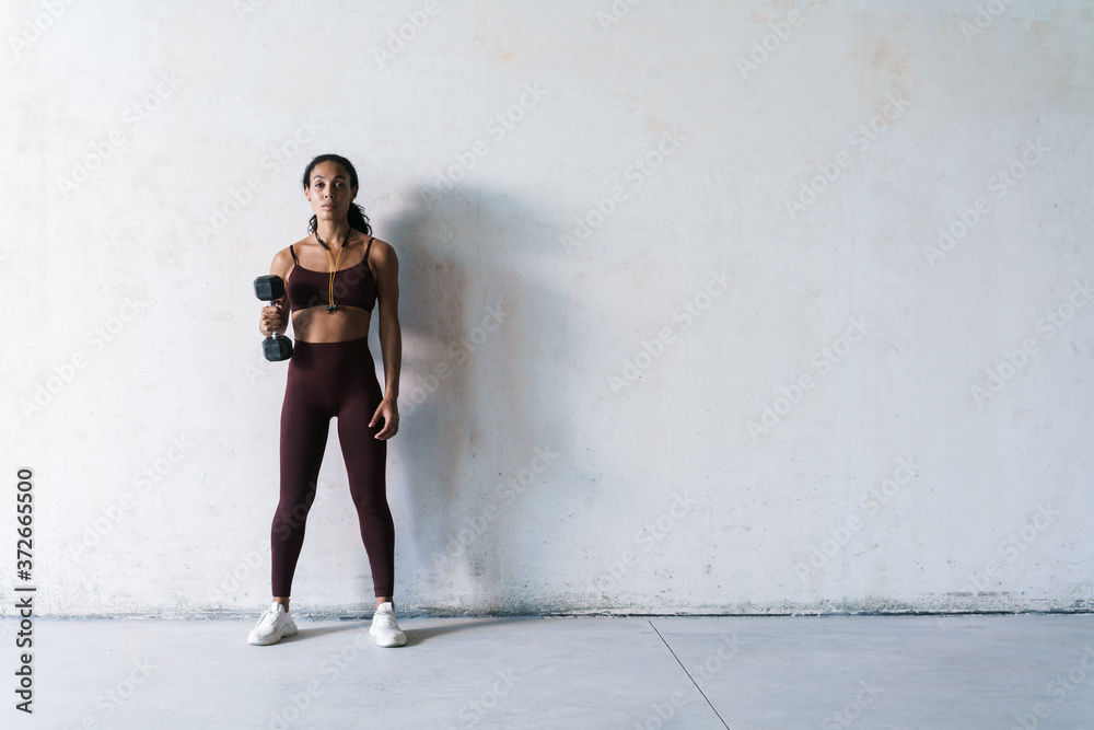 Fototapeta premium Photo of young african american sportswoman working out with dumbbell