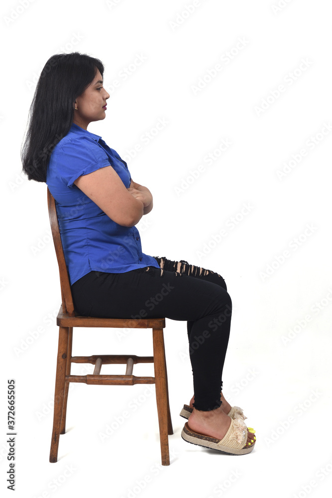 side view of portrait of a latin woman sitting on a chair in white background, arms crossed side view of portrait of a latin woman sitting on a chair in white background, arms crossed