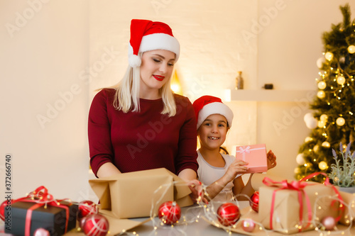 Merry Christmas and Happy Holidays. A mother and daughter prepare Xmas gifts. Baubles  presents  candy with christmas ornaments.. Christmas family traditions.