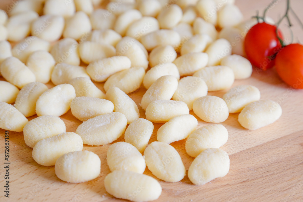 Traditional gnocchi, handmade italian pasta, with tomatoes on wooden table, natural light