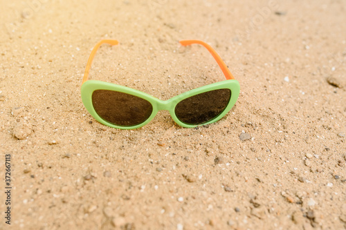 Close up green sunglasses on the sand.