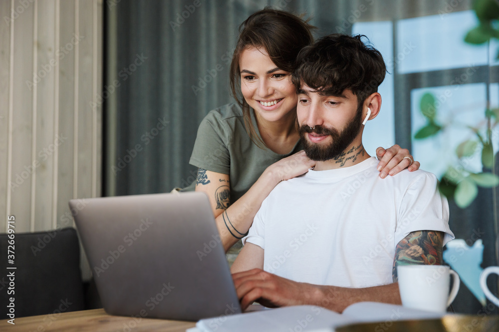 Beautiful young couple using laptop computer Beautiful young couple using laptop computer