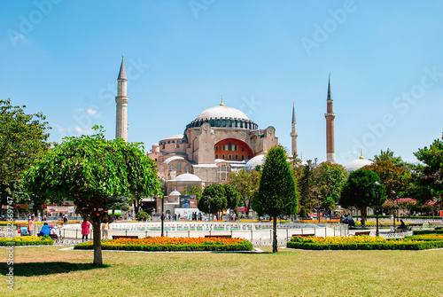 Hagia Sophia mosque in the distance. The Sultanahmet square with green trees, flowers and fountain in the foreground.