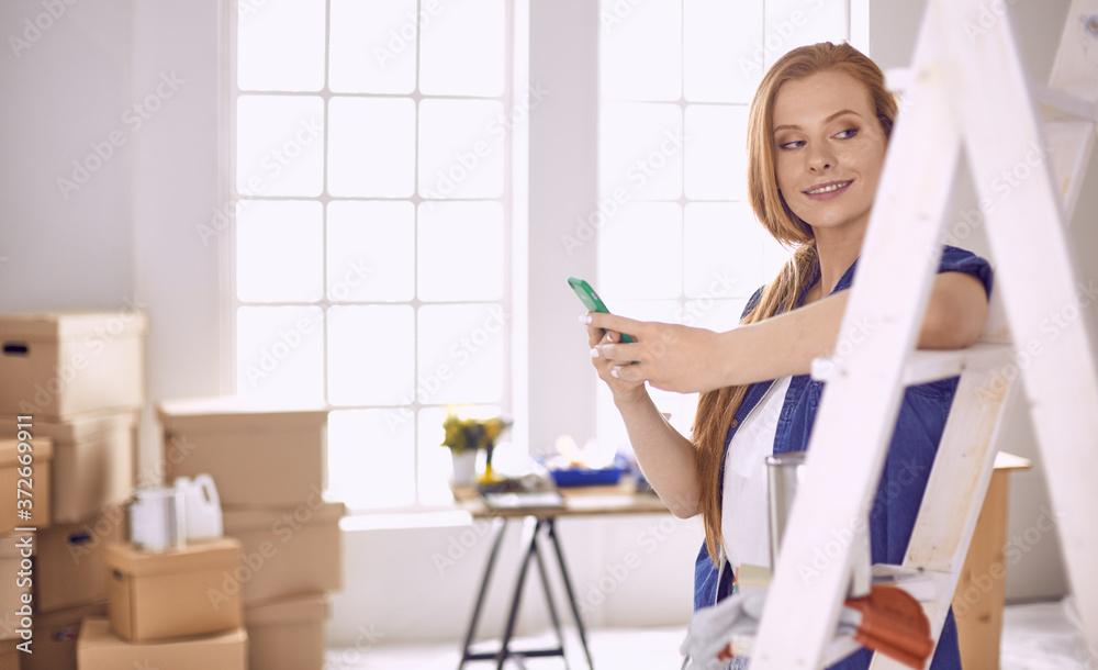 Beautiful young woman on a white wooden stepladder. Ready to repair the room. Women housework concept