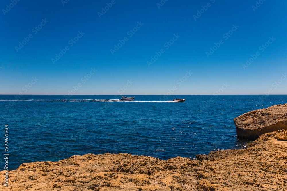 Boats between the coastline cliffs in the algarve, Portugal