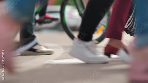 A crowd of pedestrians with a bicycle in the background cross the street. Crowded pedestrian crossing. City life. Anonymous crowd of people on the background of riding mashikhs. Slow motion