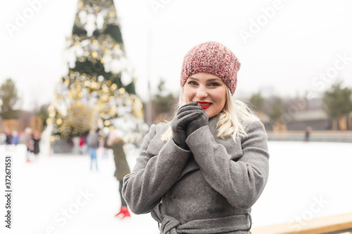 Portrait of a beautiful young woman having fun on an ice rink near christmas tree