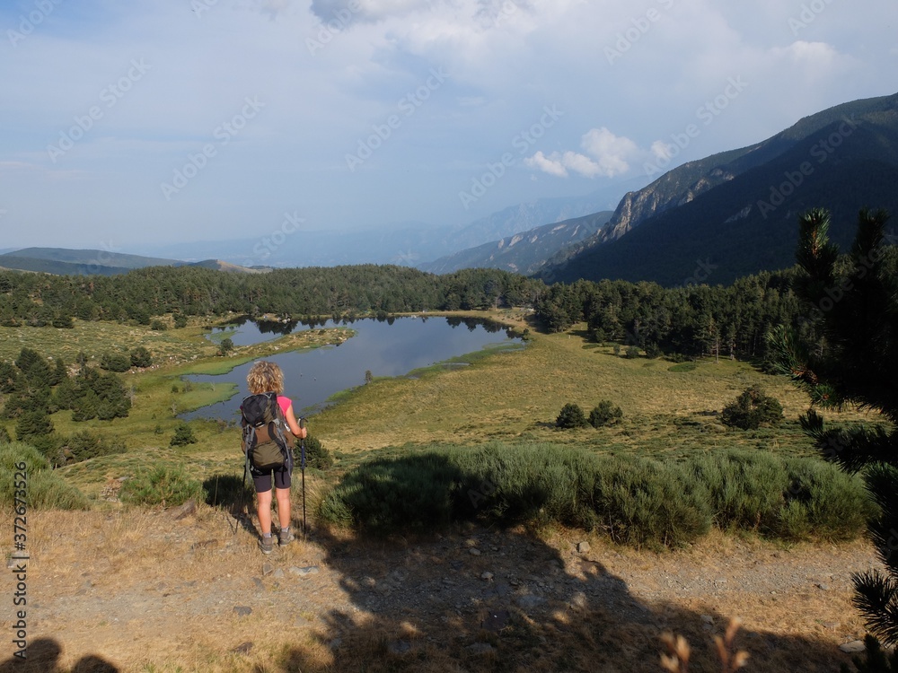 Randonnée en Pyrénées orientales lac de Nohèdes en Occitanie et jeune femme randonneuse en montagne qui marche avec bâtons