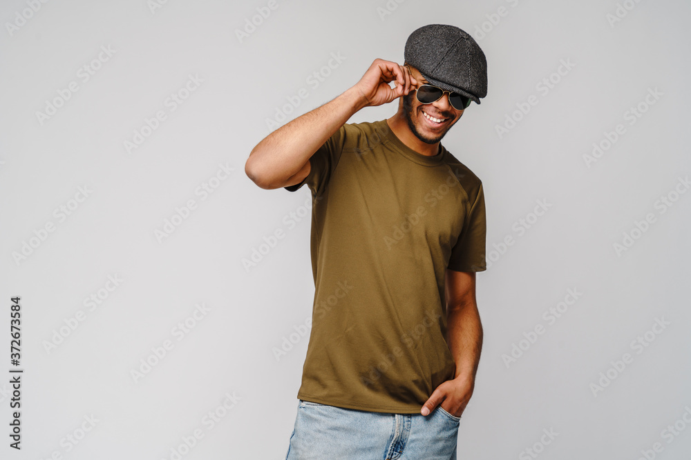 african-american young man in green t-shirt wearing sunglasses and cap over light grey background with copy space african-american young man in green t-shirt wearing sunglasses and cap over light grey background with copy space