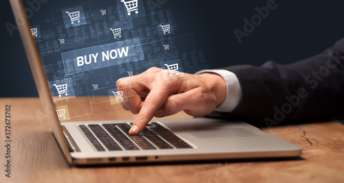 Businessman working on laptop with BUY NOW inscription, online shopping concept
