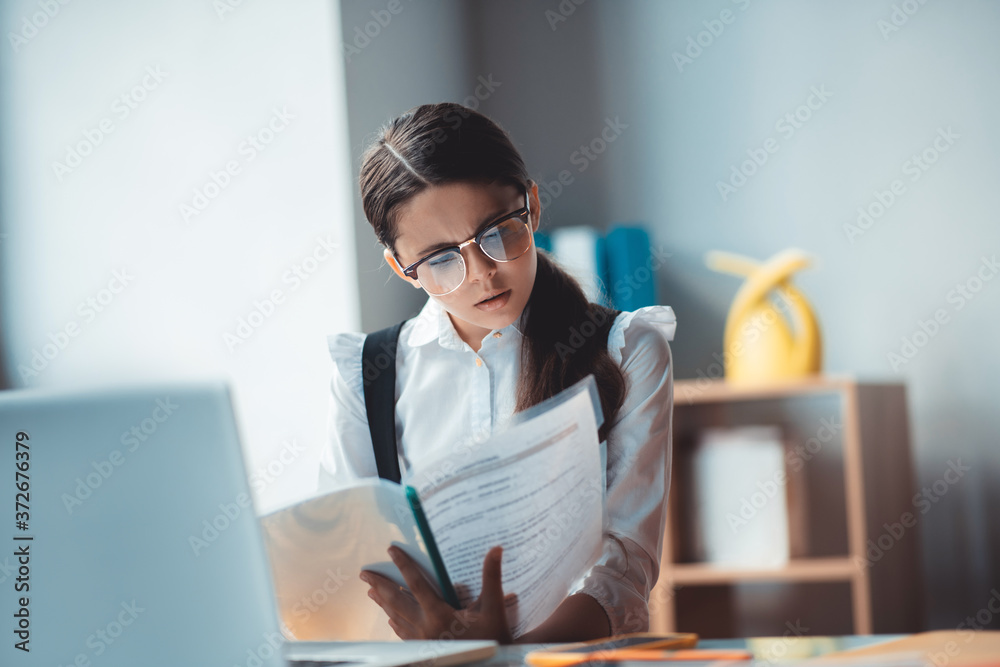 Brunette girl in eyeglasses reading a report and looking involved
