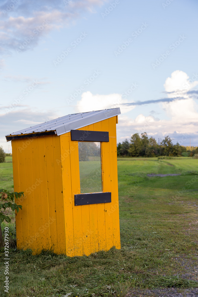 Vertical view of cute handmade yellow school bus shelter seen during a summer late afternoon in a rural area, Quebec City, Quebec, Canada Vertical view of cute handmade yellow school bus shelter seen during a summer late afternoon in a rural area, Quebec City, Quebec, Canada