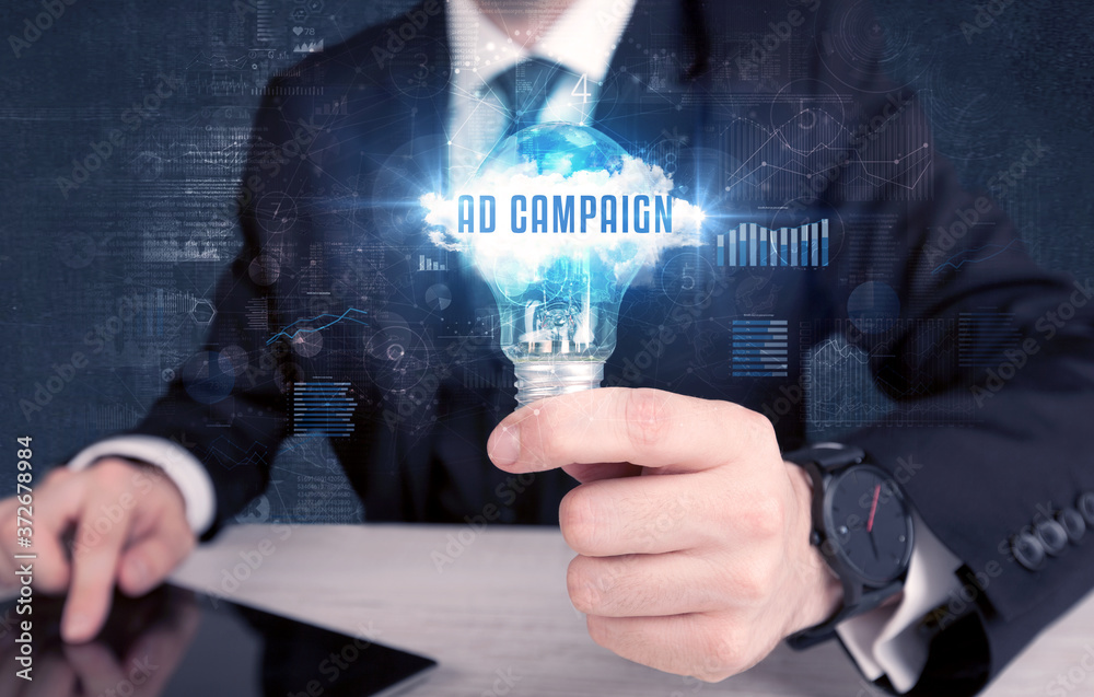 Businessman holding a light bulb with AD CAMPAIGN inscription, new business concept Businessman holding a light bulb with AD CAMPAIGN inscription, new business concept