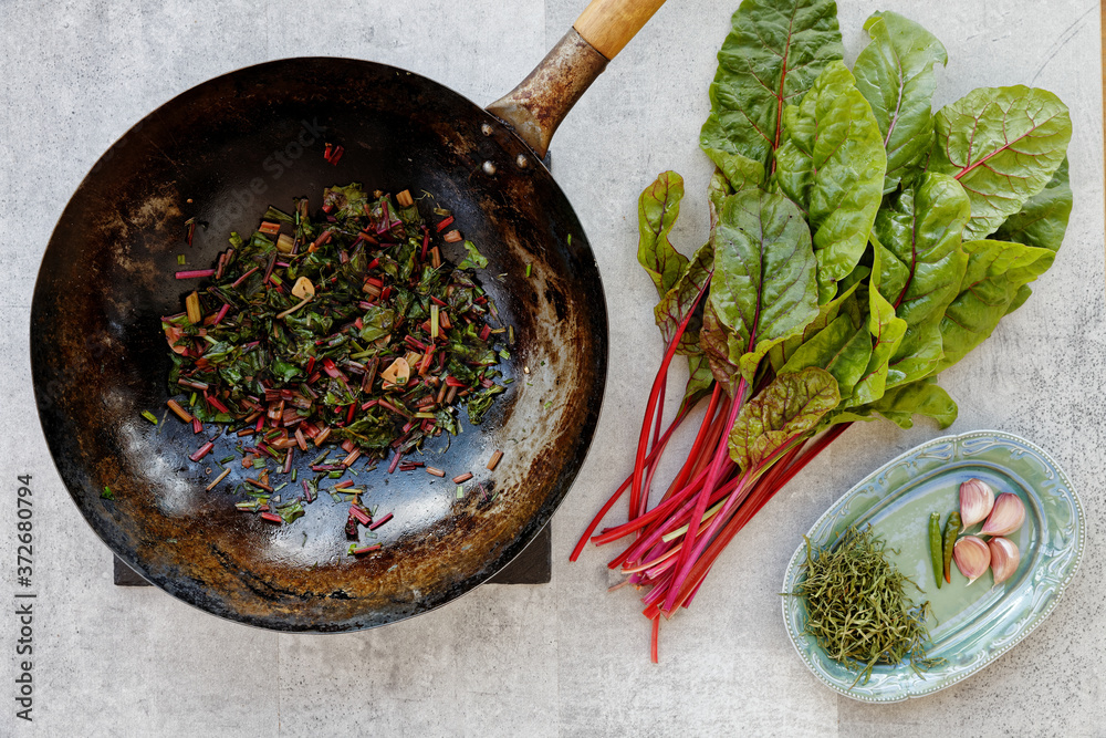 Chard Rib Eye Top view stir-fry wok dish of Swiss chard leaves with garlic and birds ...
