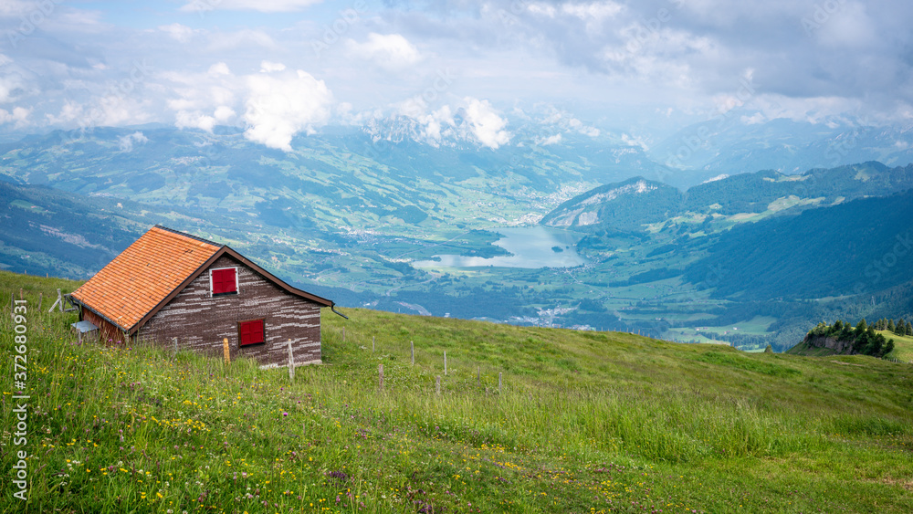 Swiss Alps panorama taken from Rigi mount summit with traditional Swiss cabin and Lauerz lake view in the distance in Switzerland