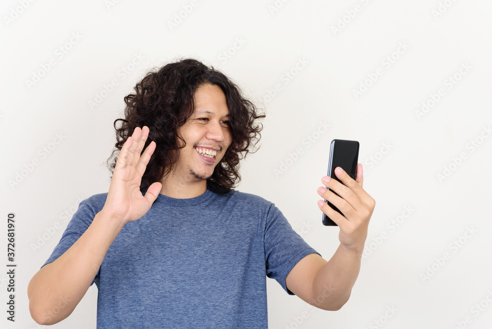Portrait of Asian man smiling and holding mobile phone for selfie, video call or playing social media Portrait of Asian man smiling and holding mobile phone for selfie, video call or playing social media