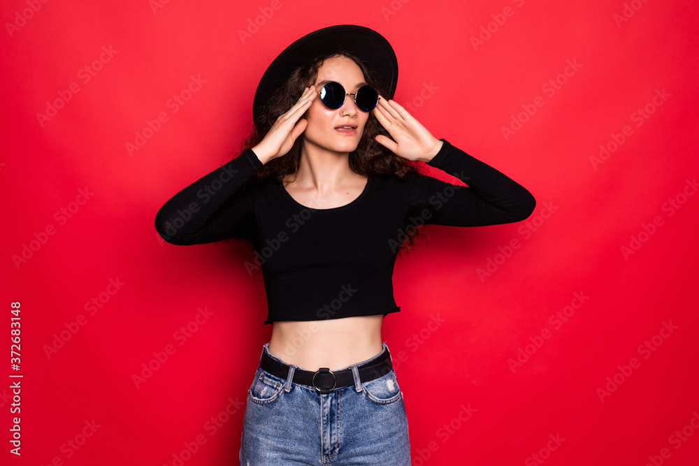 Portrait of woman in sunhat and sunglasses isolated over red background