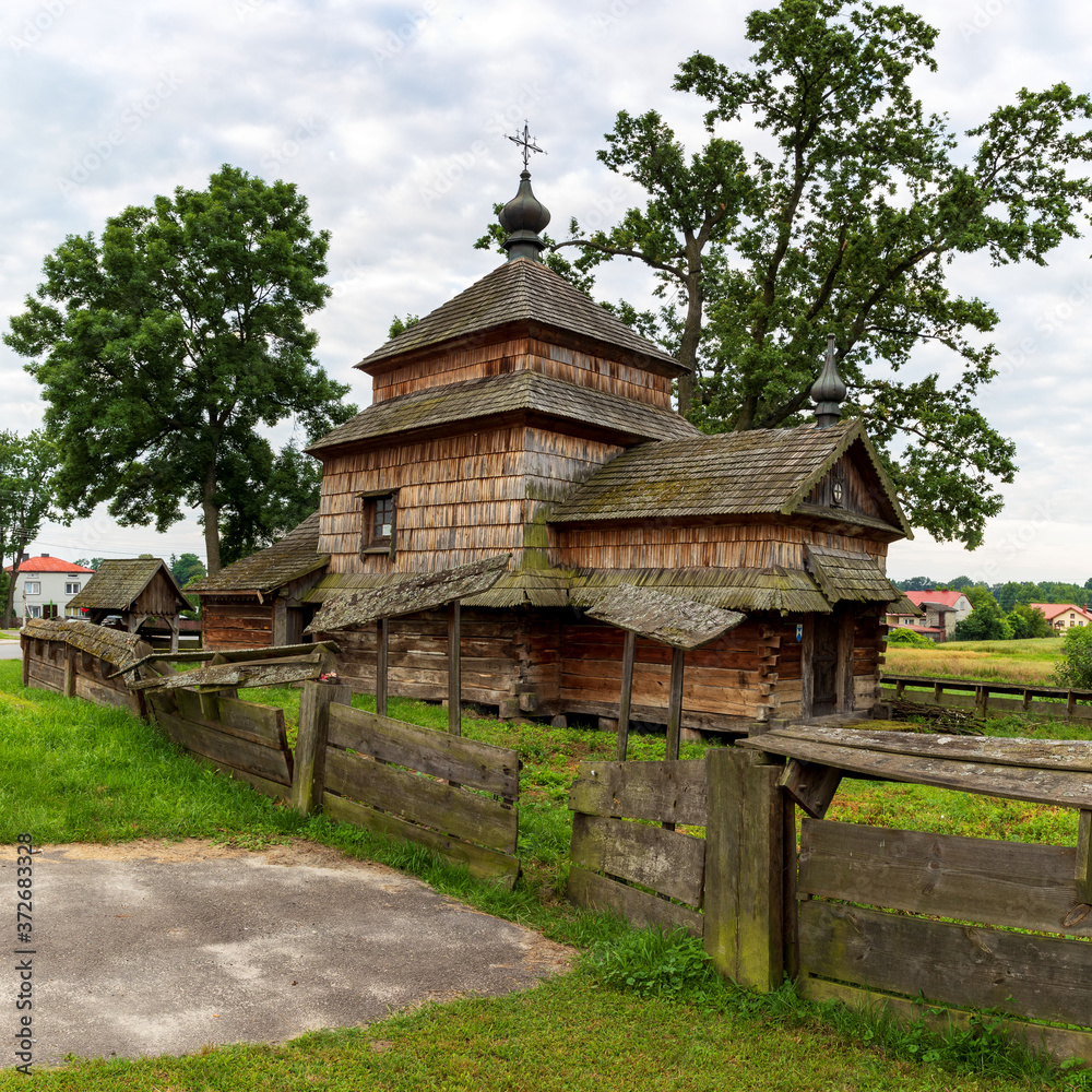 .Old wooden church architecture with wood shingle roof surrounded by wooden fence in Lukawiec village in Poland, Europe.