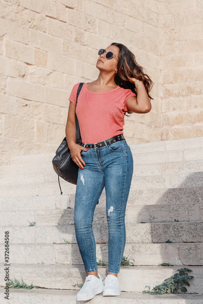 Young women wearing t-shirt and jeans going down the stairs Young women wearing t-shirt and jeans going down the stairs