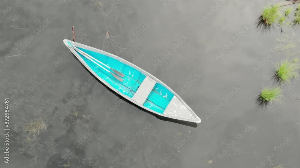 Old blue wooden boat anchored off the coast of the bay sways on calm waves. Tranquility morning by the river. Top view from drone. Beaver swims underwater. Old blue wooden boat anchored off the coast of the bay sways on calm waves. Tranquility morning by the river. Top view from drone. Beaver swims underwater.