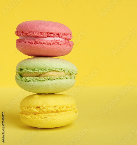 Fototapeta Naklejka Na Ścianę i Meble -  stack of baked macarons on a yellow background, delicious dessert made from almond flour