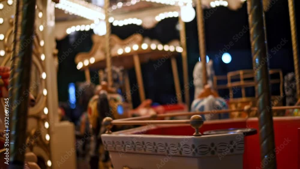 Merry go round carousel with horses spinning at funfair during night.