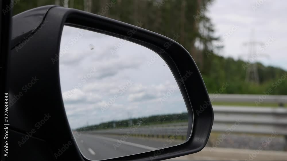 View out the rearview mirror as car drives on country road View out the rearview mirror as car drives on country road