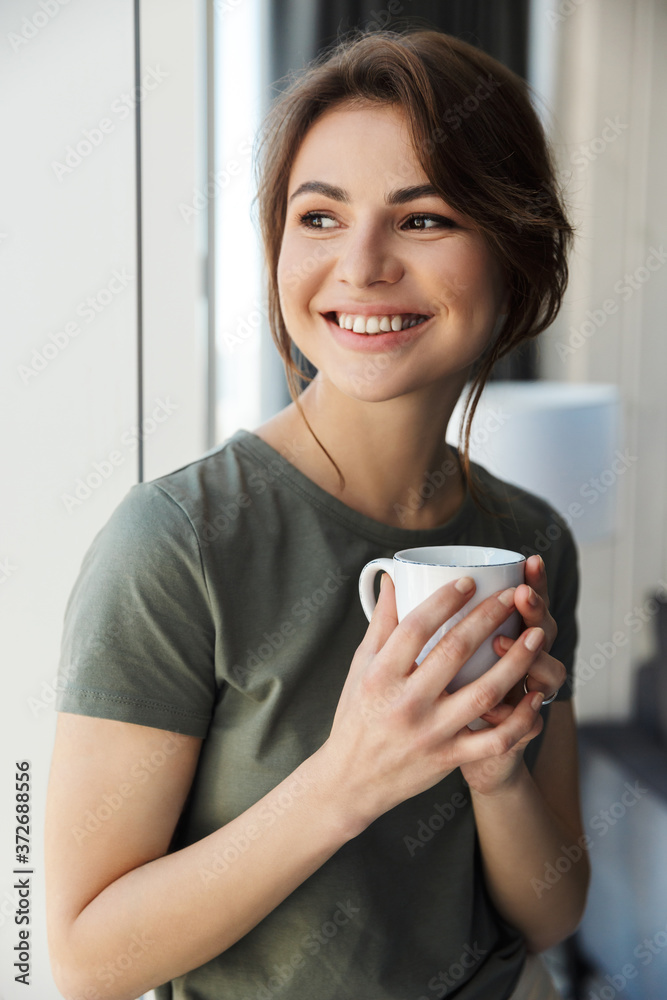 Attractive smiling young woman holding coffee cup Attractive smiling young woman holding coffee cup