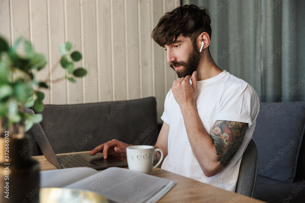 Handsome young bearded man working on laptop computer Handsome young bearded man working on laptop computer