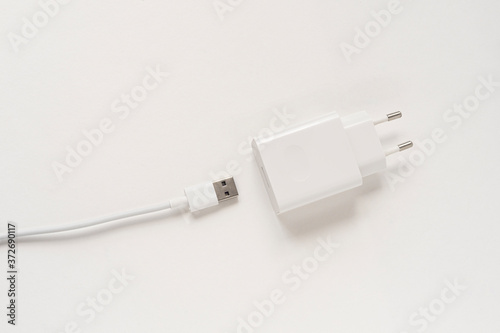 Charger for a mobile phone on a white background, the unit is disconnected from the wire top view