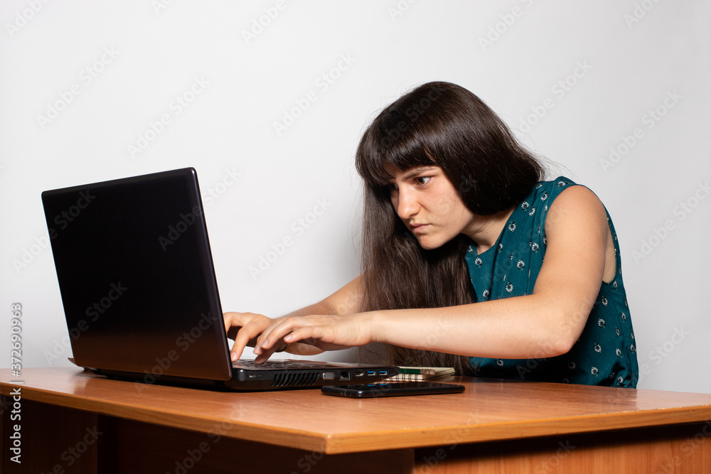The girl is a freelancer working and typing on a laptop from home. Remote work at the computer. The office of the house. Businesswoman. The girl is a freelancer working and typing on a laptop from home. Remote work at the computer. The office of the house. Businesswoman.