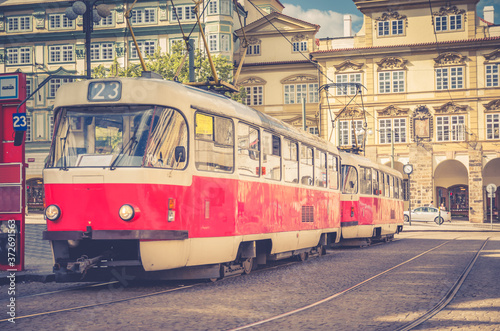 Typical old retro vintage tram on tracks near tram stop in the streets of Prague city near Sternberg palace in Lesser Town (Mala Strana) district, Bohemia, Czech Republic. Public transport concept.