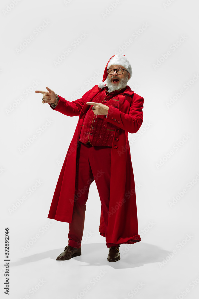 Pointing, choosing you. Modern stylish Santa Claus in red fashionable suit isolated on white background. Looks like a rockstar. New Year and Christmas eve, celebration, holidays, winter's mood