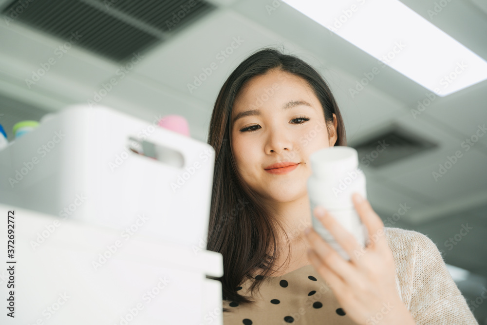 Beautiful pregnant asian businesswoman reading label on medical bottle. Beautiful pregnant asian businesswoman reading label on medical bottle.