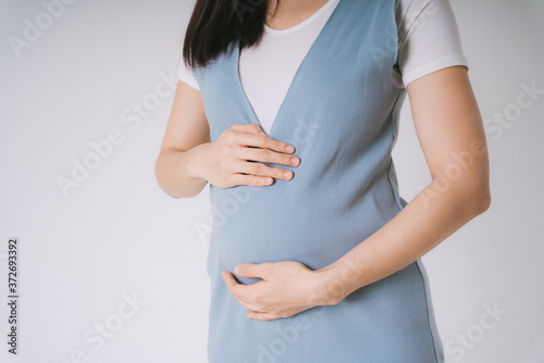 Canvas Print Beautiful pregnant asian woman holding belly isolate over white background