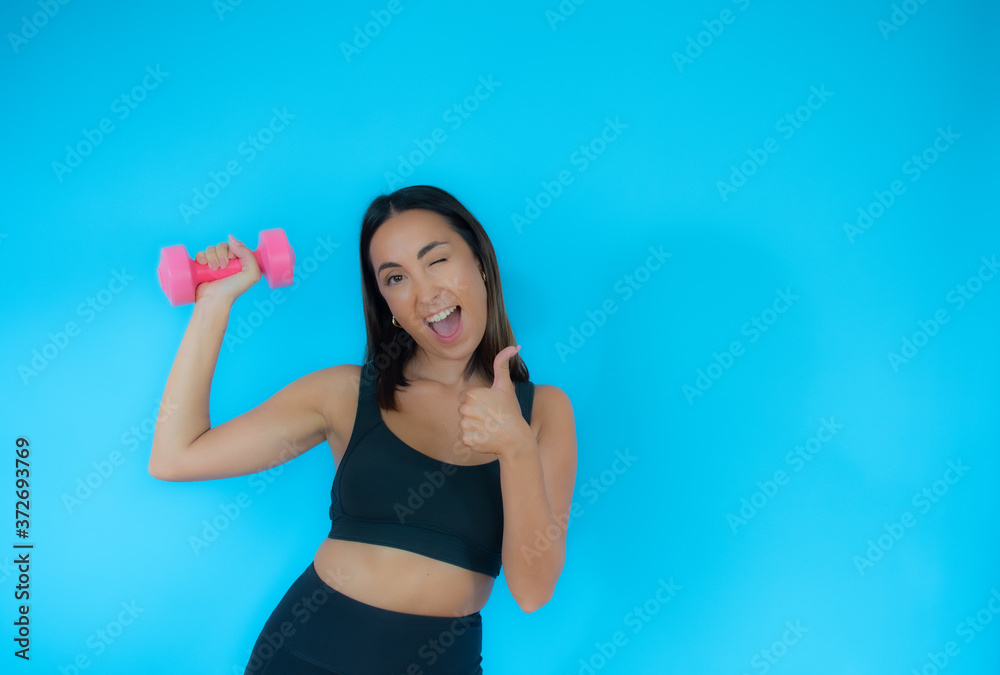 Beautiful woman in sport clothes with a dumbbell smiling Beautiful woman in sport clothes with a dumbbell smiling