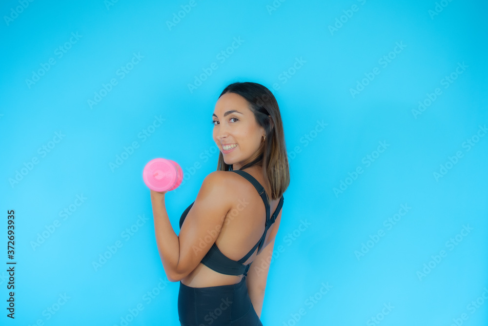 Beautiful woman in sport clothes with a dumbbell smiling Beautiful woman in sport clothes with a dumbbell smiling