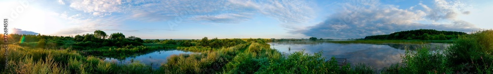 Panoramic view of a calm lake on a sunny summer day Panoramic view of a calm lake on a sunny summer day