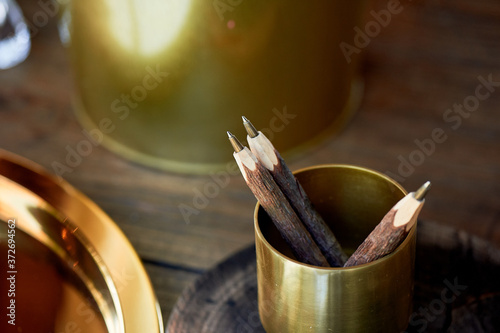 Pencils in a gold cup holder.Made like a stick of wood. Eco pens. Interesting and unusual office.