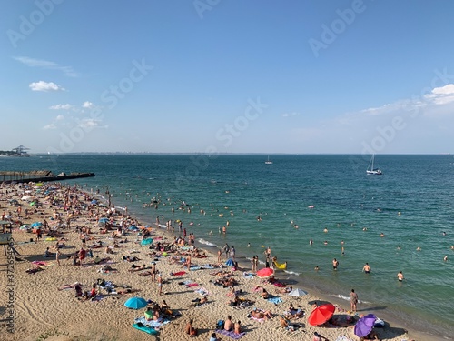 Vacationers on the sandy beach of the Black Sea. The city beach is filled with people. Men and women with children are resting on the seashore. © Сергій Колесніков