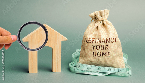 Money bag with the words Refinance your home and miniature house. Real estate concept. Business and finance. Mortgage, loan. Interest rates. Home Lending
