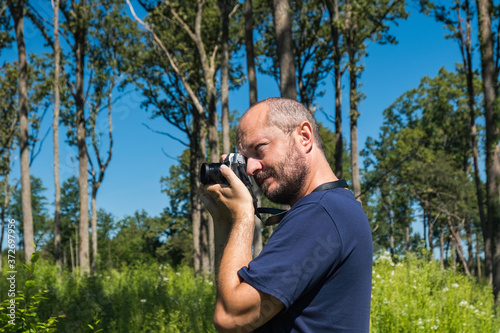 Man holding mirror less camera and taking photos in a forest in summer day