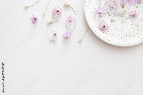 Plate with frozen flowers in ice on white background