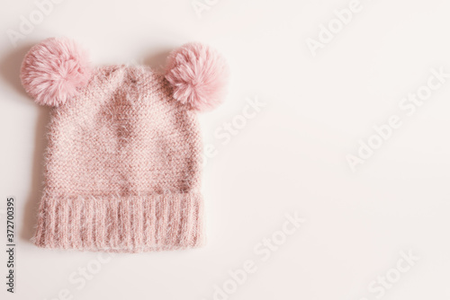 Handmade knitted hat with funny pompoms on white background, top view, copy space. Warm clothing