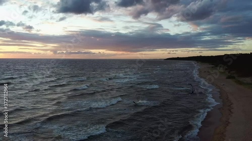 Dron Flying Over Sea in a Beautiful Sunset Kiteboarders Kiteserfing in the Backgroiund. Aerial Drone Shot. Sunrise Over the Sea. Colorful Sunset on the Baltic Sea, Latvia.