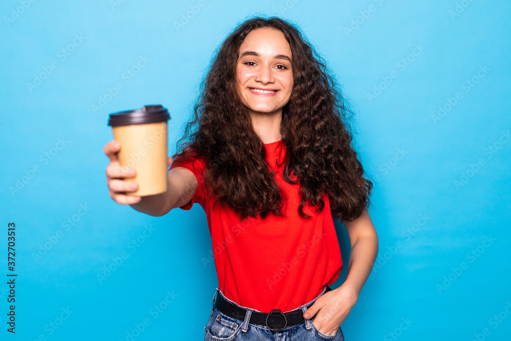 Young pretty woman holds takeout coffee stands over blue wall. Young pretty woman holds takeout coffee stands over blue wall.