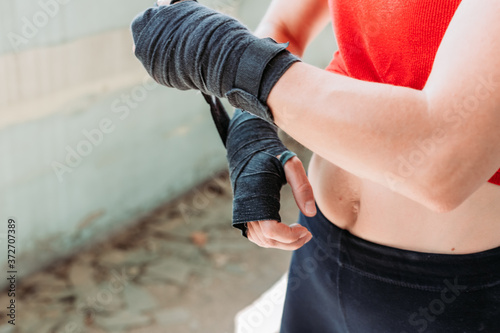 Close-up of fit, young woman putting boxing wraps, bandage on her hands.