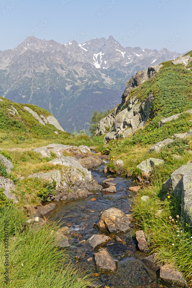 Obraz premium A small river over the cliffs and Belledonne in the background
