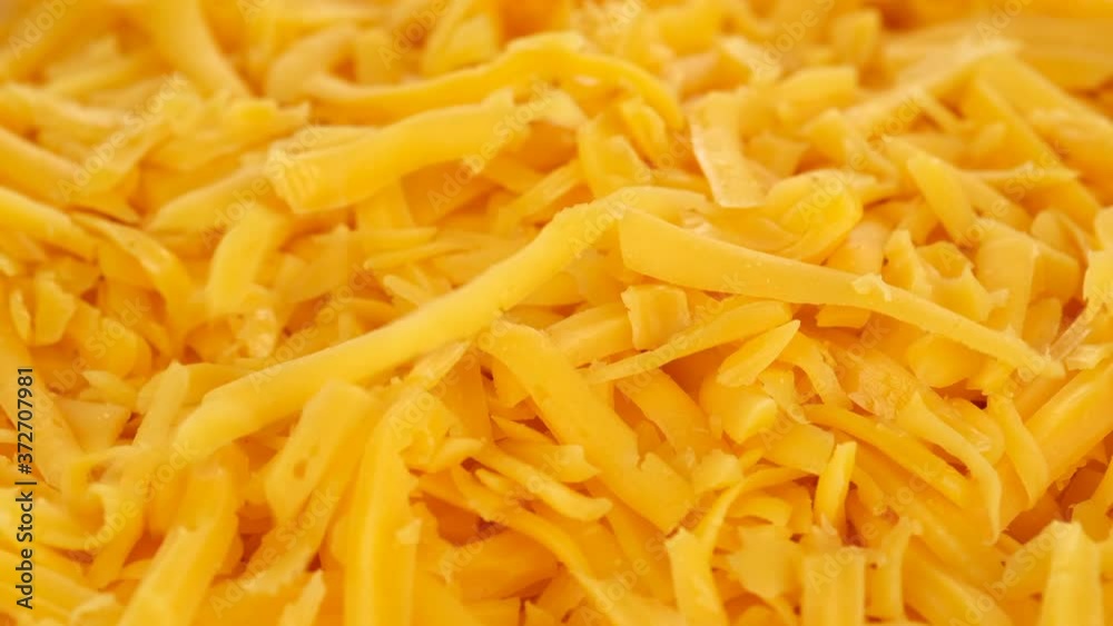 put grated cheddar cheese close up, rotating put grated cheddar cheese close up, rotating
